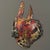 Crafted from polychrome metal, likely brass or copper, the mask represents a feline hybrid, its surface covered with hand...