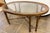 Vintage chinoiserie style oval glass top coffee table features a wood frame with carved faux bamboo legs and an X-form...