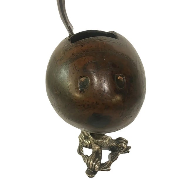 A Bugbear coconut tea caddy mounted on a silver dolphin base. Bugbear coconuts were carved by sailors on long voyages in...