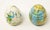 Offering a pair of ceramic glazed eggs. One egg is ivory, with blue and green spots with a tree stamped into it. The other...