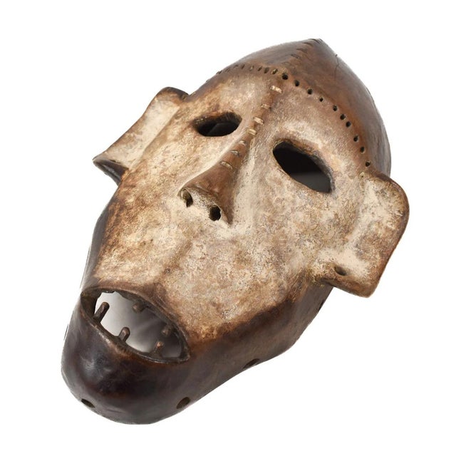 Lega masks, wooden and featuring elongated faces with a central ridge, almond-shaped eyes, and symbolic geometric...
