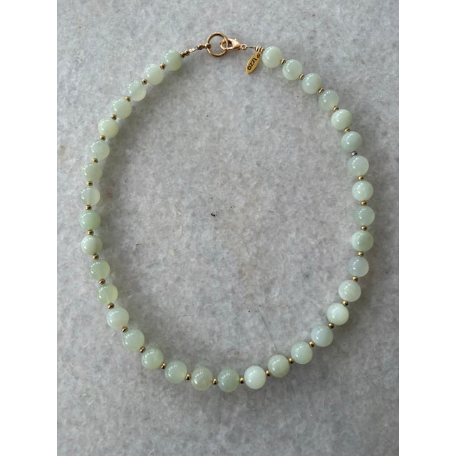 Lovely vintage light green jade beads have been carefully strung and finished with a designer gold tone clasp by Matthew...