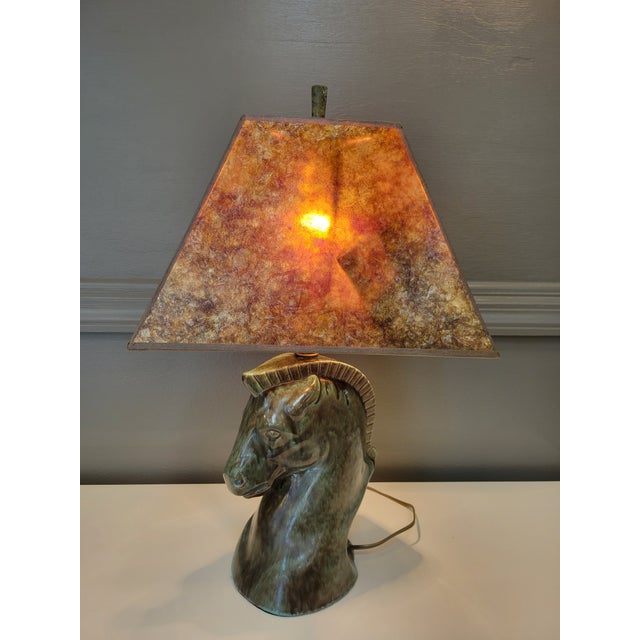 A verdigris glazed ceramic bust of a horse with a rectangular mica shade. The glaze has a rich depth of color that is...