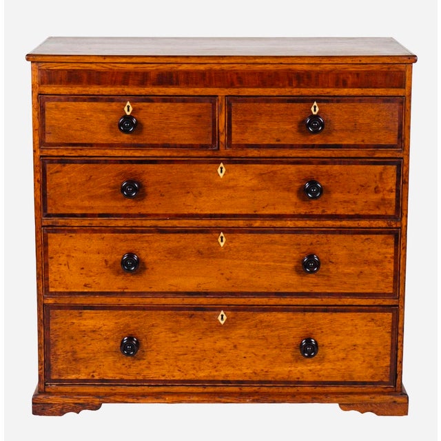 A handsome English two-tone oak chest of drawers, dating to the mid-19th century (circa 1840–1860) and crafted in the...