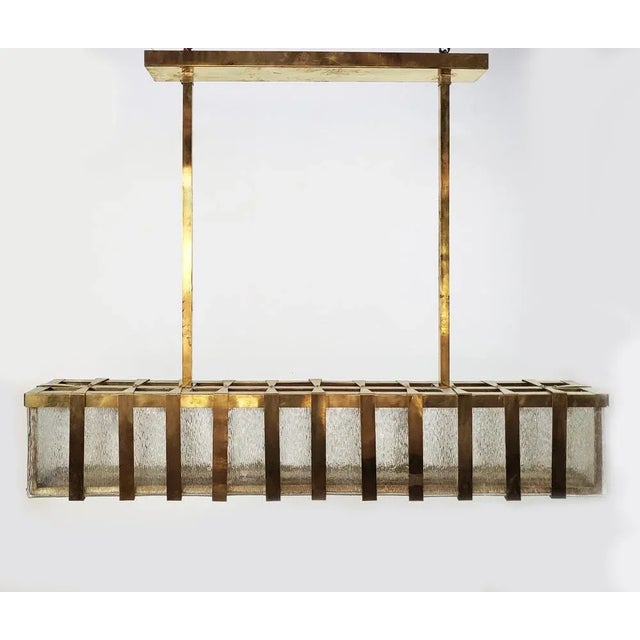 Particular vintage 70s chandelier with a rectangular shape with a structure entirely in brass and glass. Dimensions:...