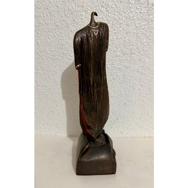 Bronze sculpture by Naomi Siegmann depicting a hanging dress decorated at the hems with geometric patterns. Piece is one...