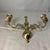 A vintage solid brass double-arm wall-mounted candle sconce featuring an ornate scroll design and a central hanging loop....