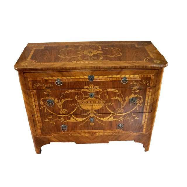 A chest of drawers complete with three large front drawers and an inlaid wood top. The sides of the cabinet feature...