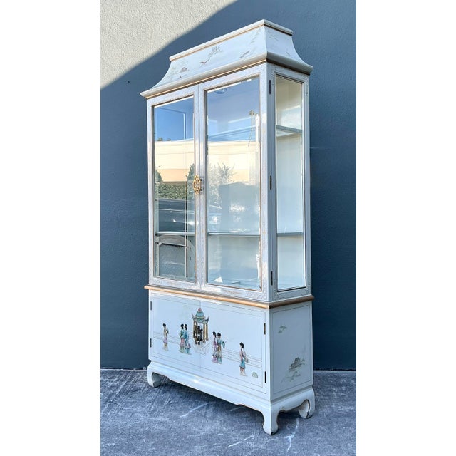 This striking Hollywood Regency hutch is a masterclass in Chinoiserie elegance, featuring a dramatic pagoda-style bonnet...