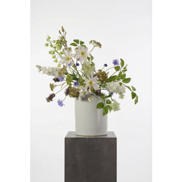 A dynamic, garden-style arrangement featuring white magnolia, lavender cornflower, and soft green fritillaria. The mix of...