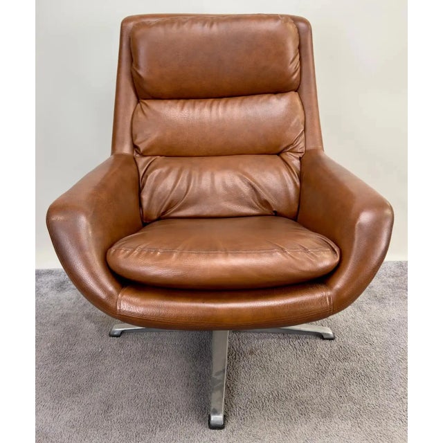 A Mid Century Modern lounge chair and ottoman from Sweden. Marrying form and function, this ensemble boasts a swiveling...