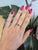 A natural red spinel glows with lively, saturated red at the centre of this solid 14K white gold ring, framed by sixteen...