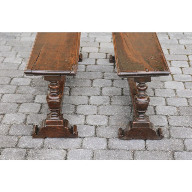 Two English Georgian period walnut benches from the early 19th century, with turned legs and cross stretcher. They are...