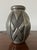 Hammered pewter vase, oval in shape, with raised geometric decorations and a distinctive hammered finish. The shapes...
