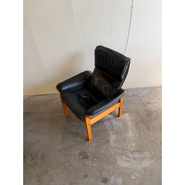 Beautiful vintage Swedish lounge armchair by Göte Möbler, featuring supple black leather upholstery paired with a solid...