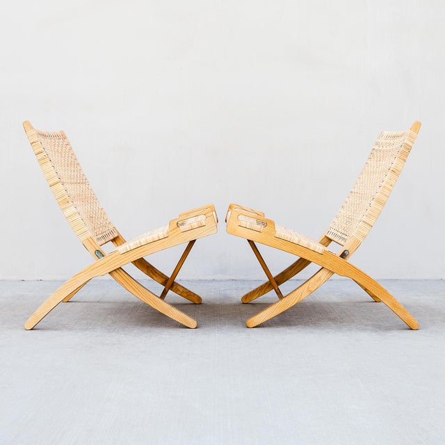 An expertly restored pair of Hans Wegner Model 512 Folding Chairs in ash and rattan, made in Denmark by PP Mobler....