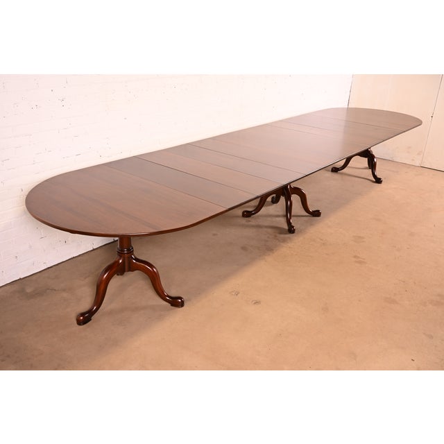 A gorgeous Georgian, Regency, or Queen Anne style solid mahogany triple pedestal extension dining table By Henkel Harris...