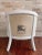 White barrel-back armchair upholstered with back and sides made from luxury brand dust bag fabric. Inside is off-white...