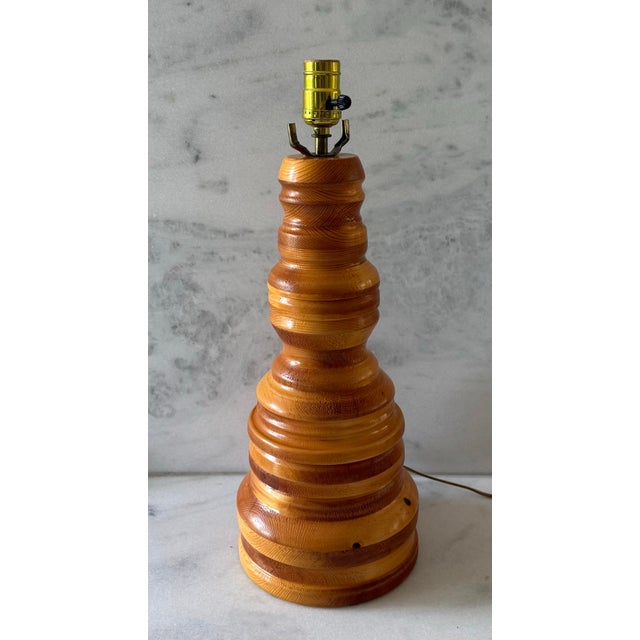 Vintage turned wood table lamp made from solid knotty pine wood with a clear finish. With natural knots and grain and warm...