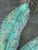 Large wall sculpture features a teal leaf crafted from crushed glass on and-textured resin designed to resemble natural...