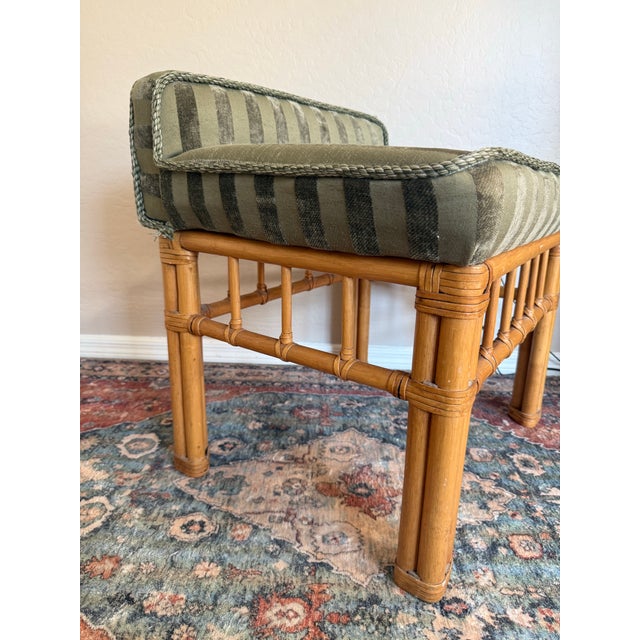 Vintage bamboo and rattan stool featuring a warm honey-toned frame with wrapped joints and decorative spindle detailing....