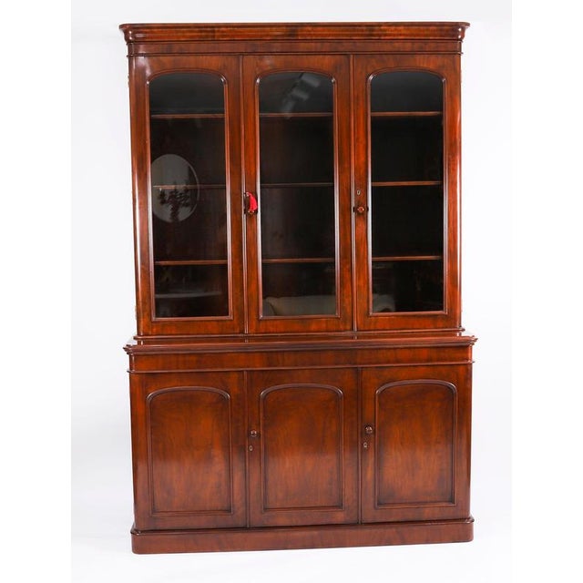 This is a beautiful antique Victorian flame mahogany four door library bookcase, masterfully crafted in rich solid...