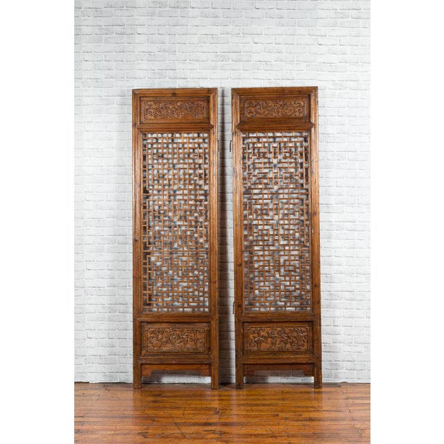 A pair of Chinese antique carved screens from the 19th century, with fretwork motifs and low-relief panels. Created in...