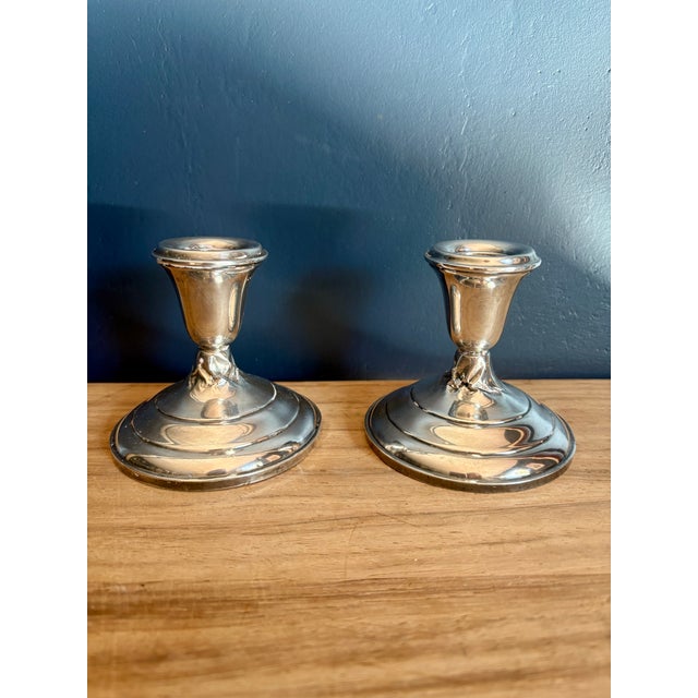 Pair of low American sterling silver candlesticks with weighted bases. Flared urn-form cups with rolled bobeche rims,...