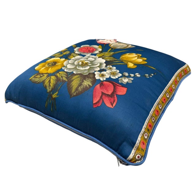 Vintage upholstered footstool featuring a bold floral textile in shades of cobalt blue, yellow, white, and coral mounted...
