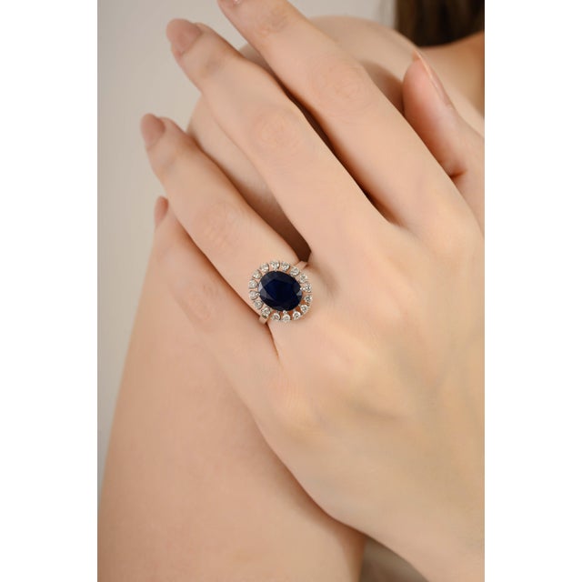 This exquisite cocktail ring showcases a 4.5 CTW oval-cut deep blue sapphire, radiating timeless elegance. The centerpiece...