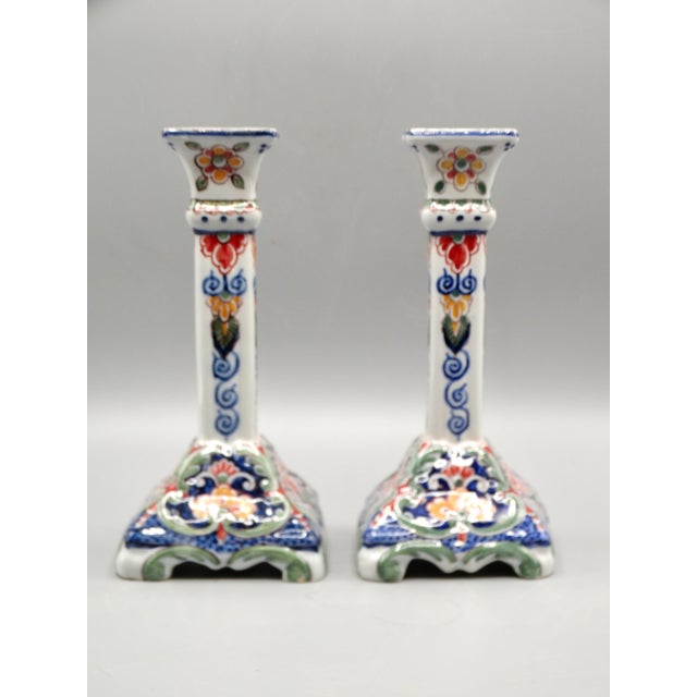 Pair of early 20th-Century Dutch Delft candlesticks 9" in height. They are hand painted in a colorful floral garden design...