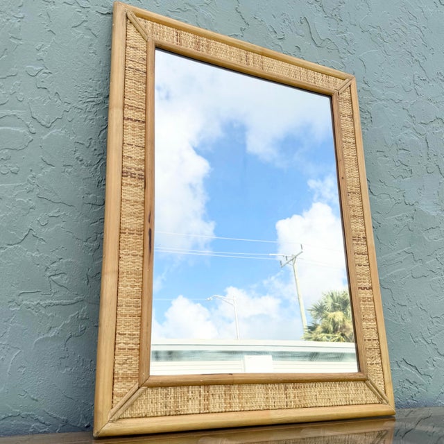 Charming vintage wall mirror featuring a natural woven wicker frame accented with smooth rattan trim. The rectangular...