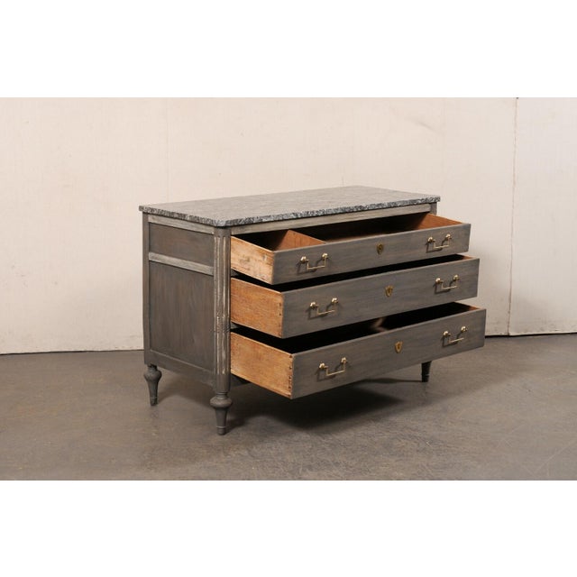 A Neoclassical French carved and painted wood commode, with original marble top, from the 19th century. This antique chest...