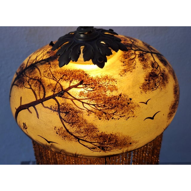 Finely reverse-painted glass shade with beading on a patinated bronze or brass base. The top has an unusual mechanism that...