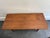 A mid-century modern solid wood coffee table with rounded corners, tapered splayed legs, and an H-stretcher with ribbed...