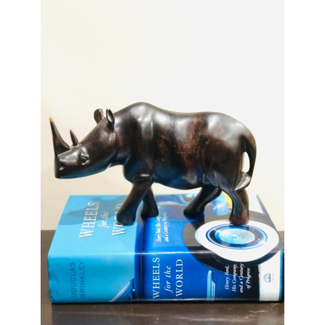 A well rendered ebony carved wood rhinoceros in a rich dark brown almost black with some light brown color a beautiful...
