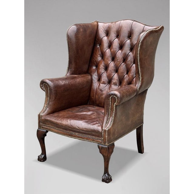 This high-quality, untouched 19th-century brown leather button-back wing armchair is designed in the George III style. The...