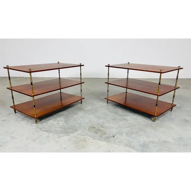 A pair of Elgant 3-tier side tables having mahogany shelves that feature stunning grain patterns connected by spun brass...