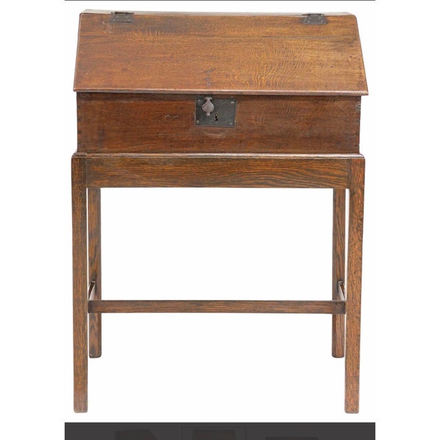 A fine English Georgian oak slant-front box on stand, dating to the late 18th or early 19th century.. This versatile piece...