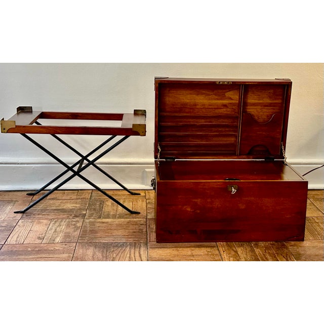 A distinctive campaign-style portable writing chest raised on its original folding stand. Crafted in warm-toned wood with...