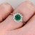 A Zambian emerald glows in a lush grass green at the centre of this solid 14K white gold ring, encircled by fourteen...