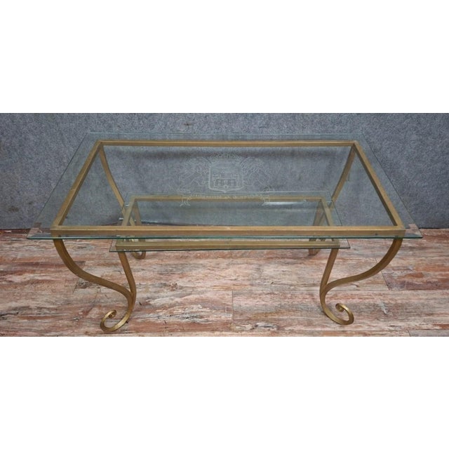 Brass and engraved glass coffee table, in the style of Maison Jansen, circa 1970. An elegant coffee table with a gilt...