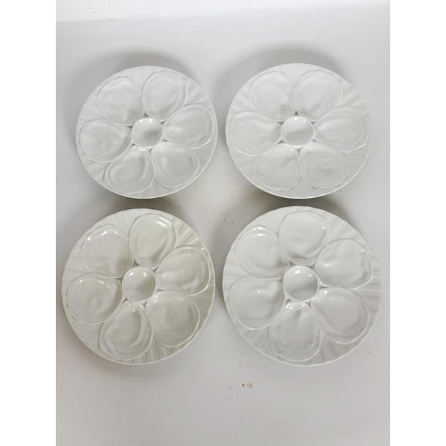 A beautiful set of four white glazed ceramic oyster plates, each featuring six oyster compartments and a central well for...