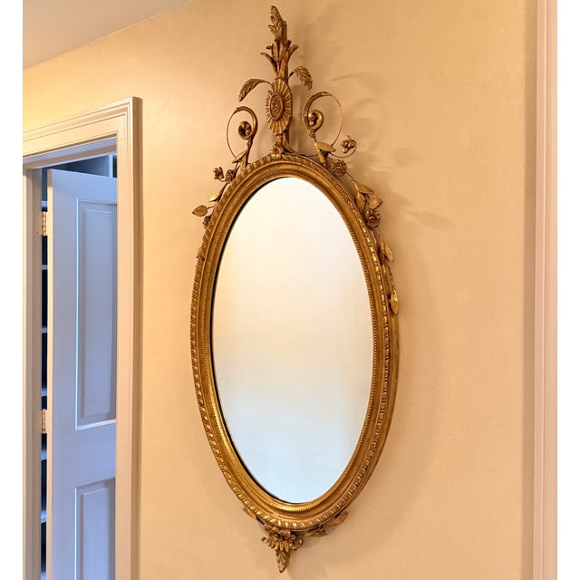 Adams Style Oval Wall Mirror Beveled glass supported by a gilt frame. 23” x 49”