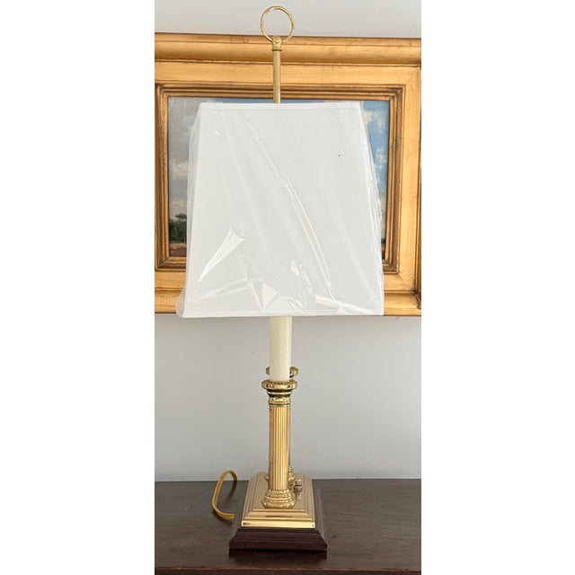 This is a classic French-style bouillotte table lamp featuring a polished brass finish, two fluted candlestick lights, and...