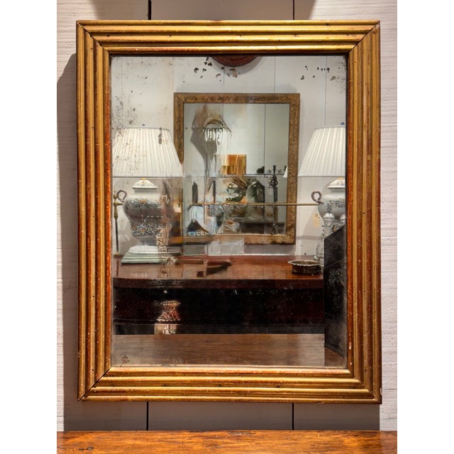 French Directoire period mirror with a deeply molded rectangular gilt frame. The aged mirror plate shows scattered foxing,...