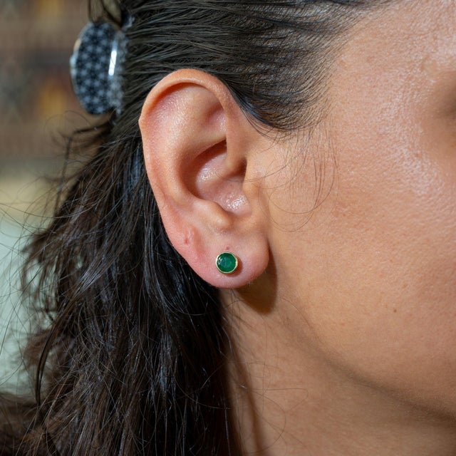 A matched pair of Zambian emeralds glows in lush green in these solid 14K yellow gold bezel-set solitaire stud earrings....