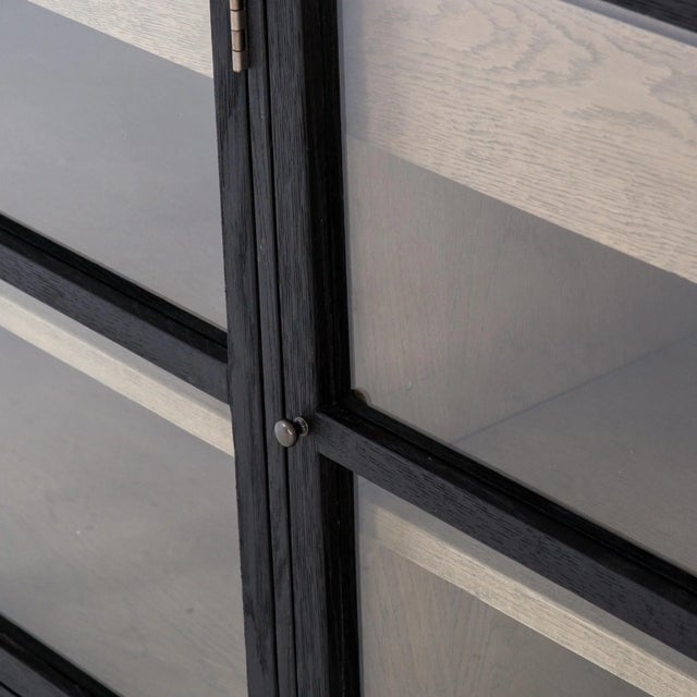 Black drifted oak frames lighter interior shelving for subtle but striking contrast. Glass doors allow for prized...