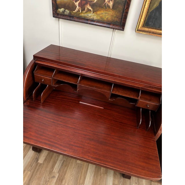 An impressive antique mahogany butler's desk featuring a distinctive curved cylinder front, an extensively fitted writing...