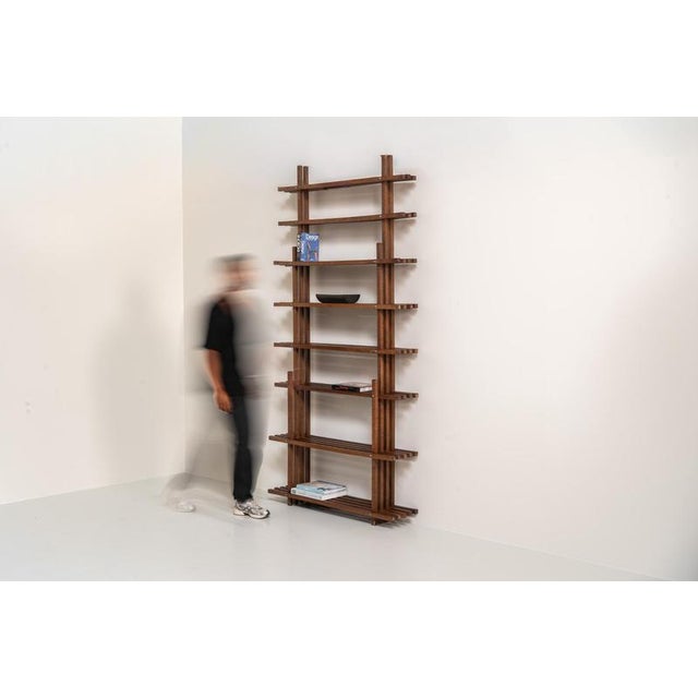 Sculptural wengé slat bookcase (Europe, 1960s). A sculptural bookcase defined by the rhythmic interplay of solid wengé...